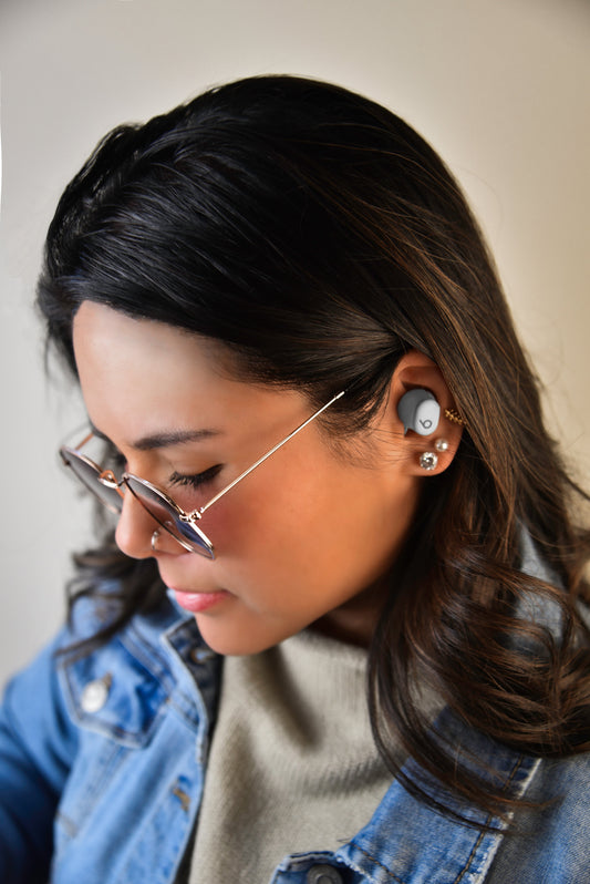 A woman wearing Beats Solo Buds in Storm Gray on the left ear..